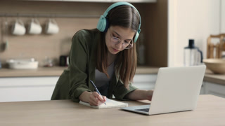 Teen girl e-learning using laptop in domestic kitchen