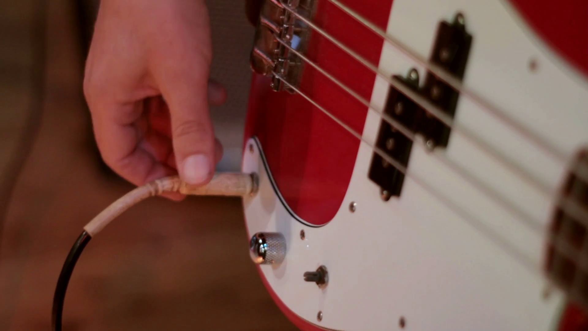 Plugging a jack lead from amp into a bass guitar in a music recording