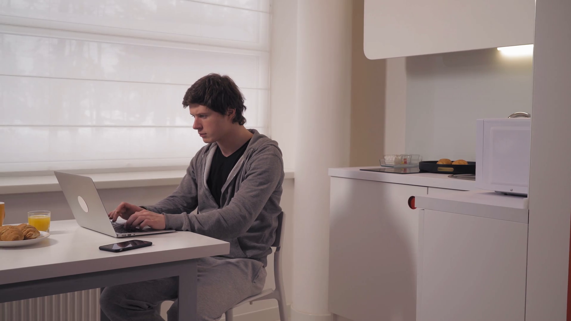 Man Sitting At The Desk With Cup And Croissant On White Place Male Working Looking On Screen Computer In Kitchen Businessman Computing At Home In The Morning Stock Video Footage Storyblocks