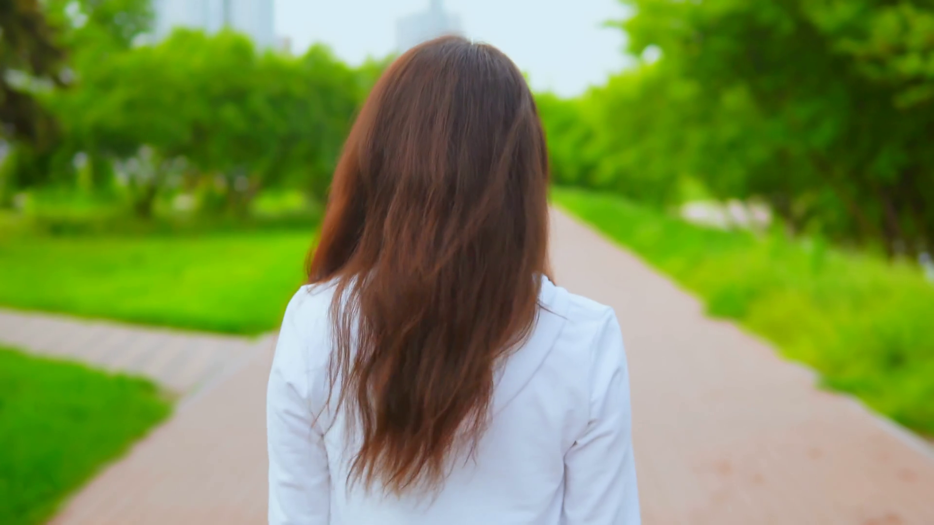young woman wearing casual white hoodie walks on the street with nature background green trees surrounded road