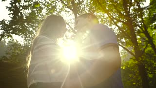Loving Couple Walking Outdoors Near a Waterfall. Morning light shines into the camera. Slow motion