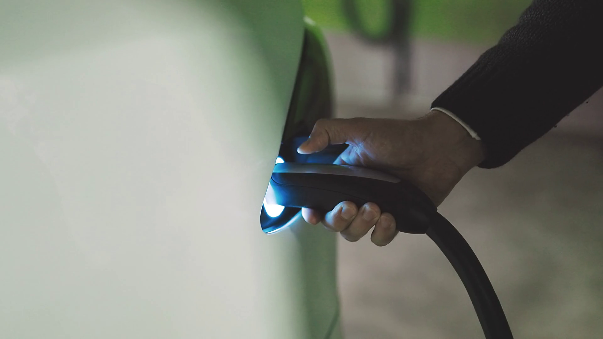 Unplug electric car charging cord connector. Unrecognizable man