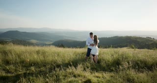 Adorable couple embracing and kissing in a beautiful mountain region. Summertime love story.