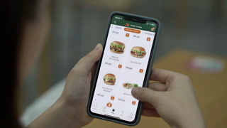 Samara, Russia - 24 August 2026: Woman scrolls through burgers and wraps menu in Vkusno i Tochka restaurant app on smartphone, former