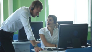 Phone operator works in an office call center, helping his colleague.
