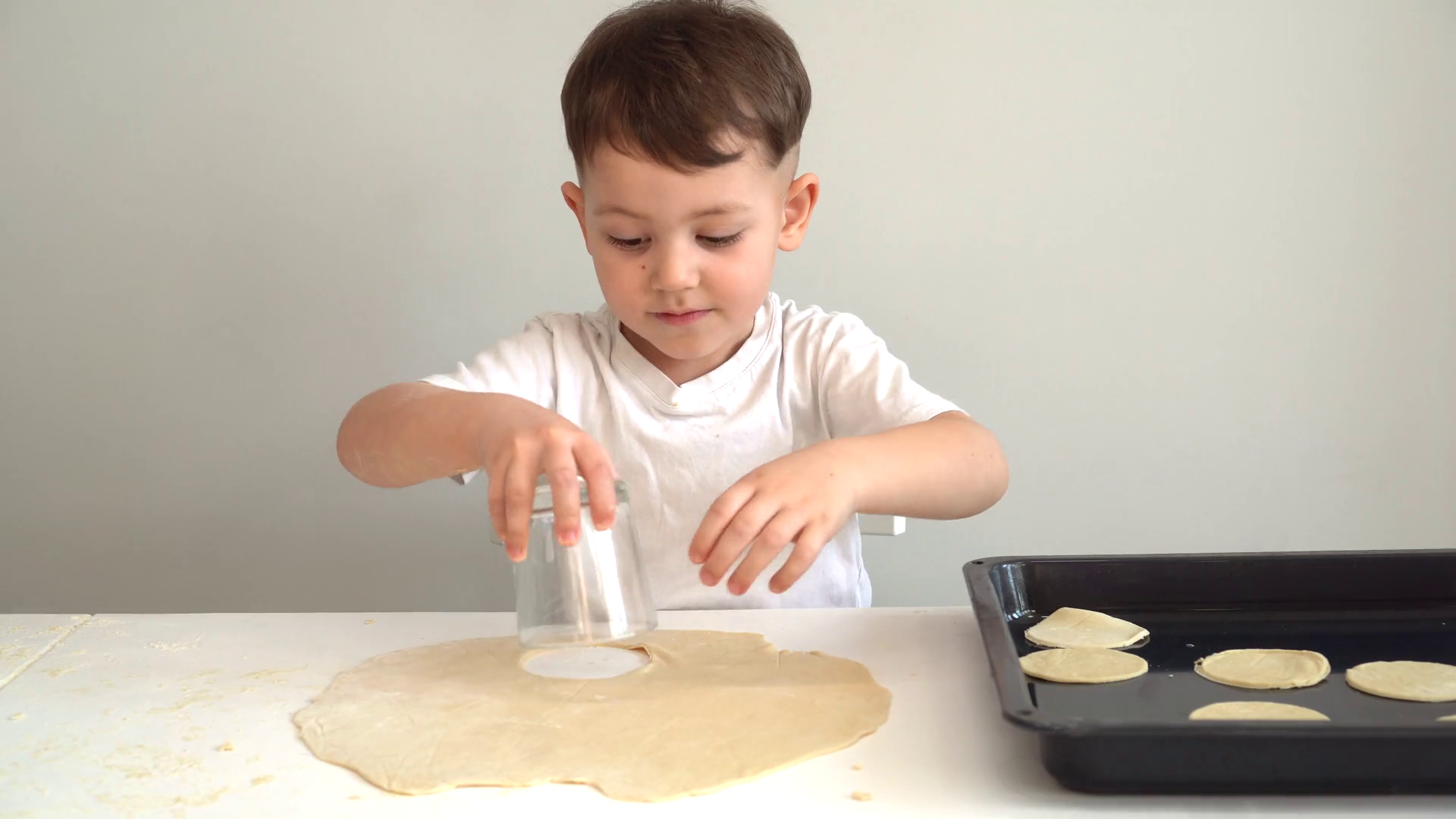 little boy making cookies from dough and putting them on baking sheet Stock Video Footage 0012