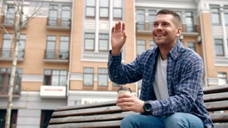 Looking directly at camera for a close up shot and smiling and waving.