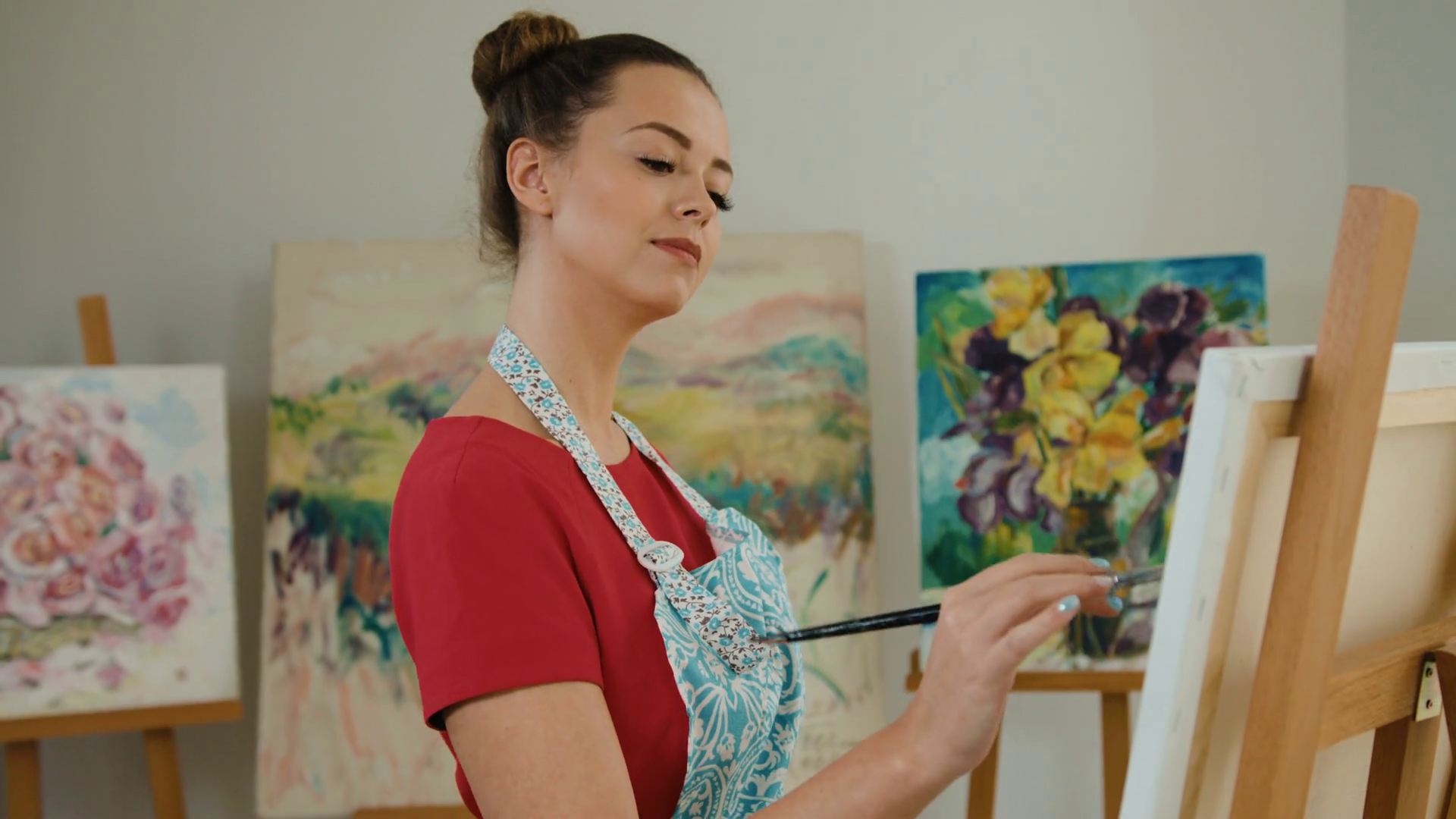 Young happy artist with paintbrush in hands , posing on camera while