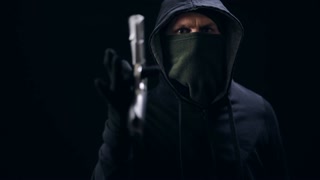 Robber in mask rolling gun on finger