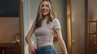 Lady reflection fastening jeans checking weight loss progress closeup. Smiling woman trying big clothes waist size at home