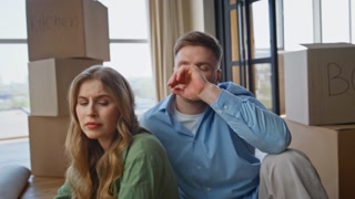 Exhausted family sitting surrounded packed carton boxes moving new apartment closeup. Tired man embracing fatigued woman in purchased house