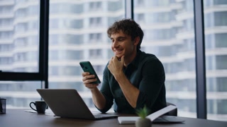 Entrepreneur browsing banking app cellphone sitting laptop workplace closeup. Successful businessman smiling receiving mobile notification