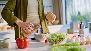 Woman hands pouring granola adding milk at light cuisine closeup. Focused housewife cooking breakfast switching videos on tablet device