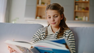 Smart kid flipping fairytale resting sofa closeup. Adorable little child looking pictures in book learning alone at living room. Positive