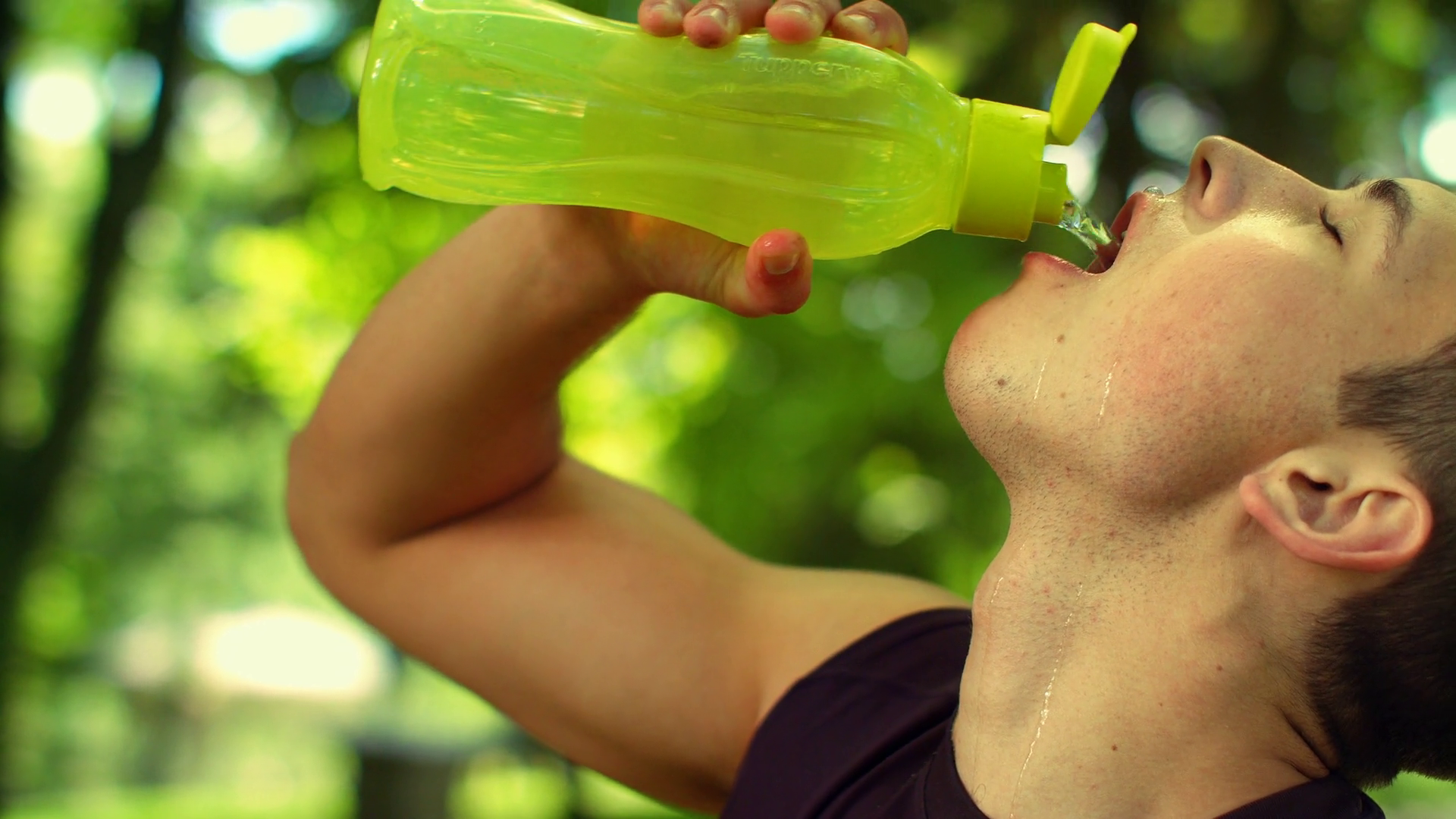 Athletic sport man drinking water from bottle. Cold drink after outdoor