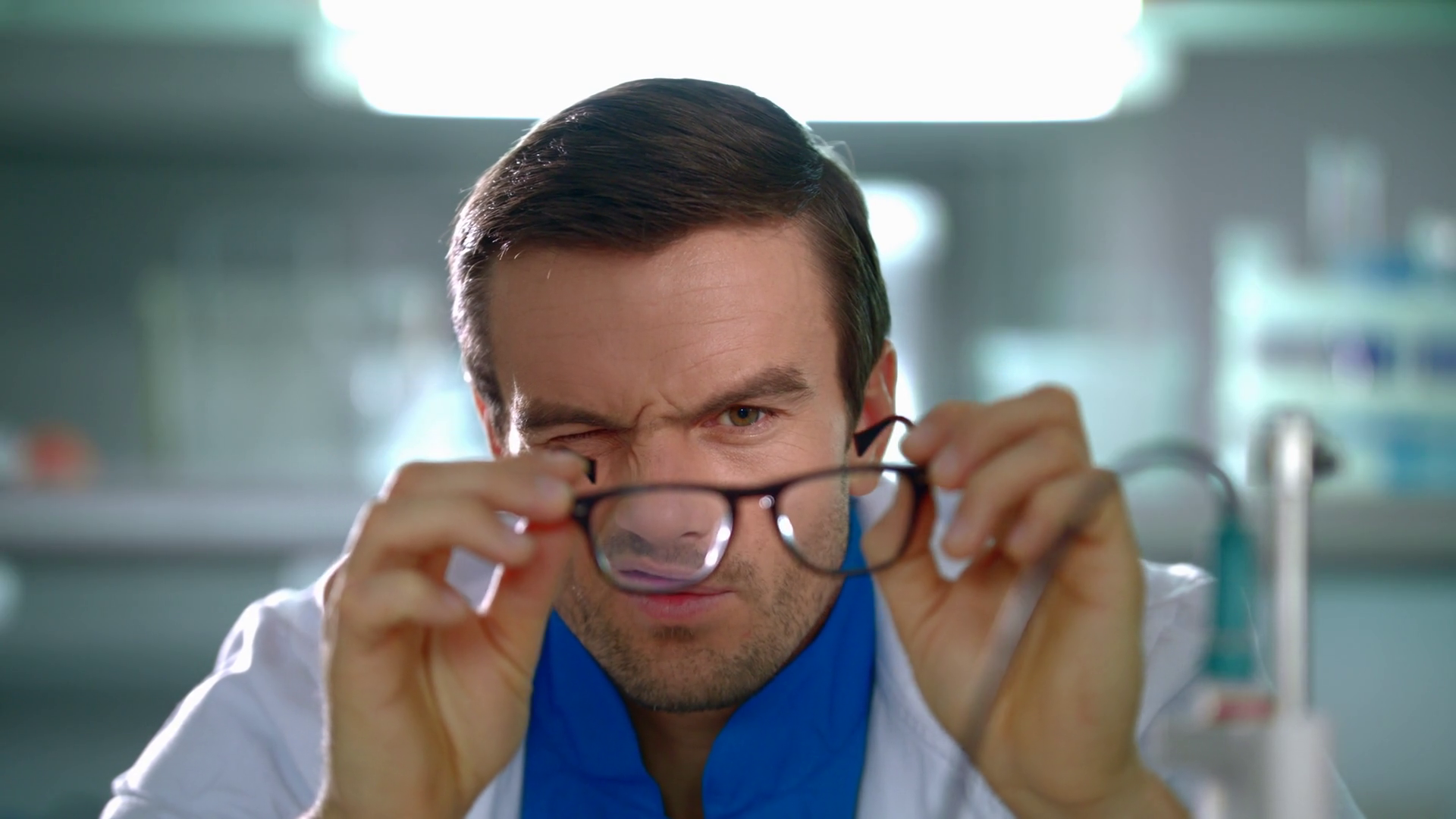 Doctor looking through glasses. Close up of researcher squints eyes