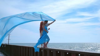 Kissing couple on sea pier. Pregnant couple kissing on sky background. Love couple kissing behind blue cloth. Happy woman kissing man. Expecting parents. Romantic couple on sea vacation