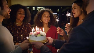 Friends celebrate birthday in cafe with surprise cake. Excited people sing to festive woman at fancy restaurant. Happy emotion concept.