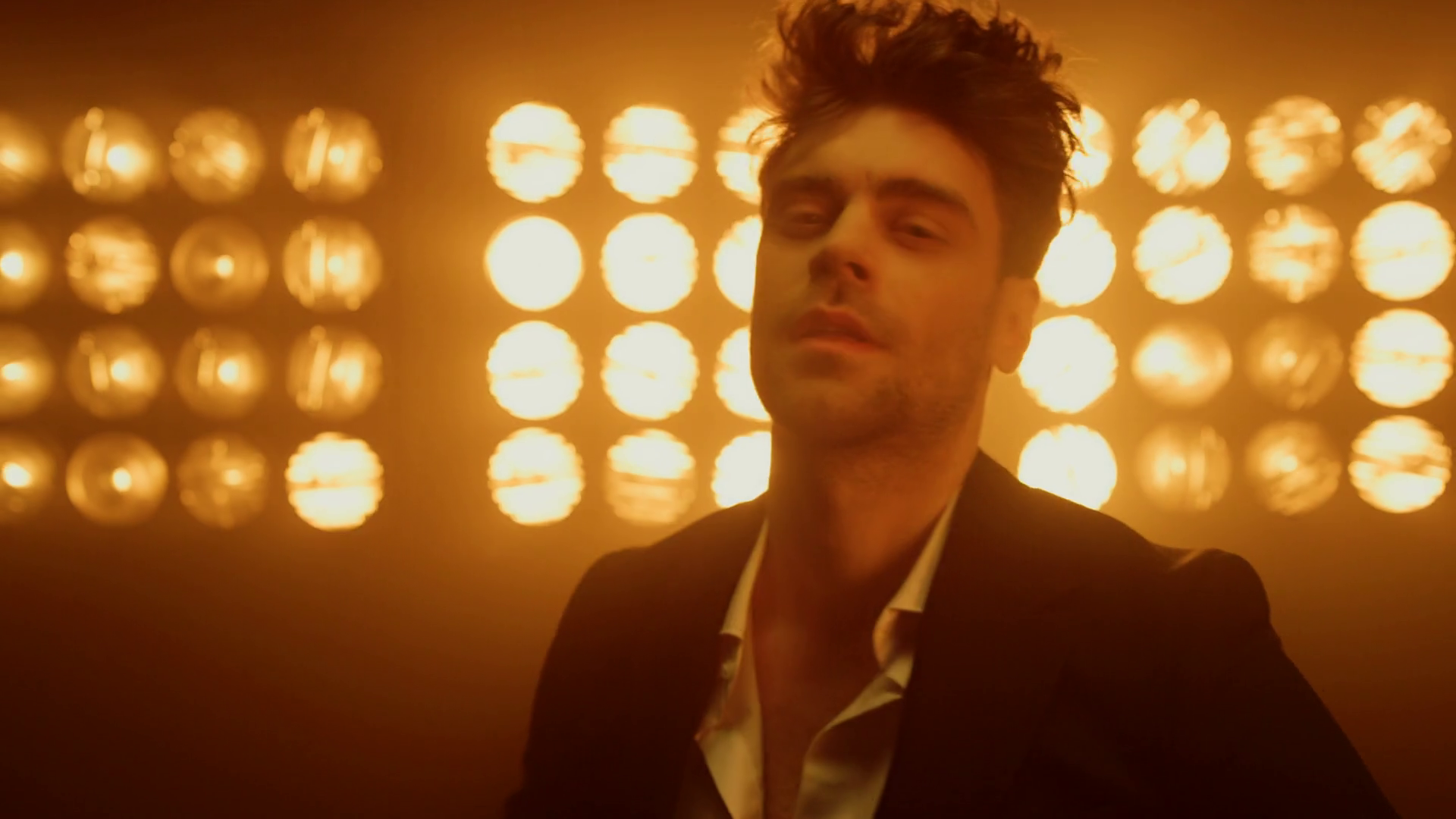 Seductive man with stylish haircut posing while looking camera in night