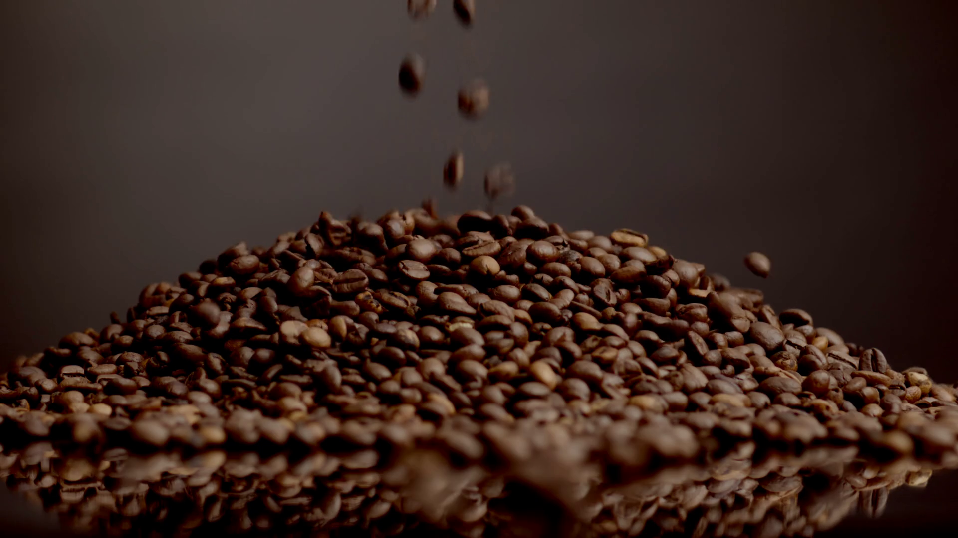 Coffee beans pouring on top heap close up. Roasted caffeine grains