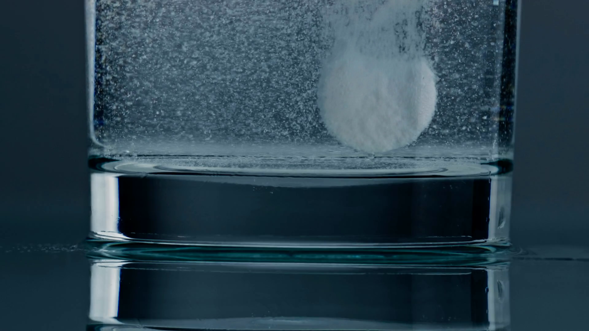 Effervescent tablet water dissolving closeup. Fizzy white pill flowing