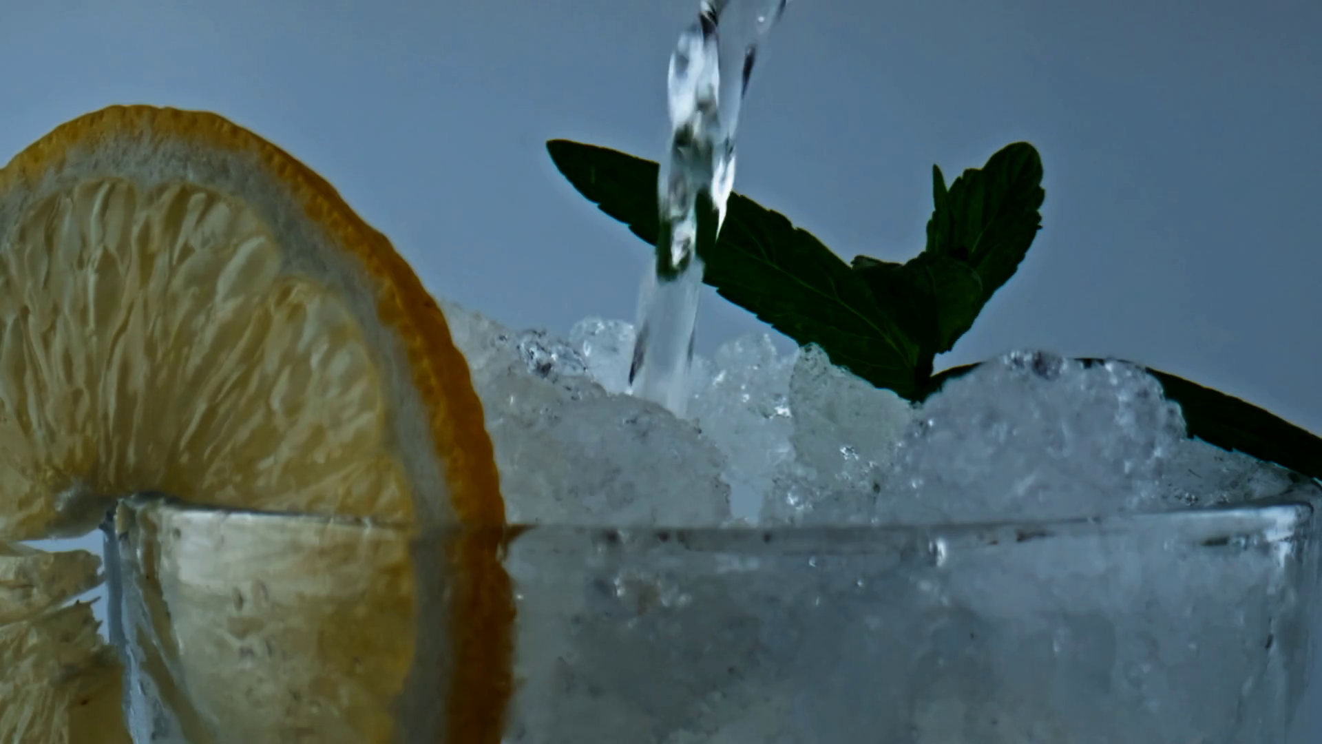 Closeup water pouring lemonade drink. Soda filling iced citrus mint beverage. Making summer