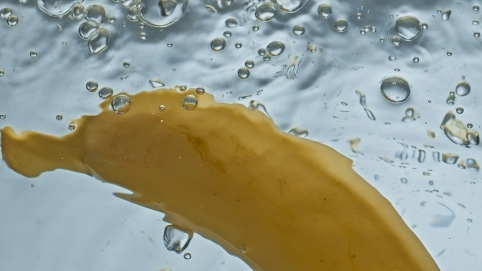 Closeup fresh banana water floating in light background. Yellow tropical fruit falling bouncing