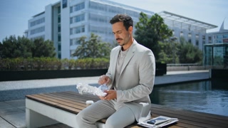 Elegant businessman unpacking lunch in sunny park