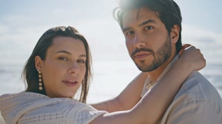 Relaxed lovers posing beach looking camera in front sunny sky close up. Tender woman putting hands on husband neck standing summer beach