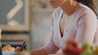 Woman noting information from webinar looking on laptop screen closeup. Focused businesswoman writing in notepad working computer at office