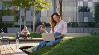 Happy Freelancer woman typing on laptop in city park on a sunny day