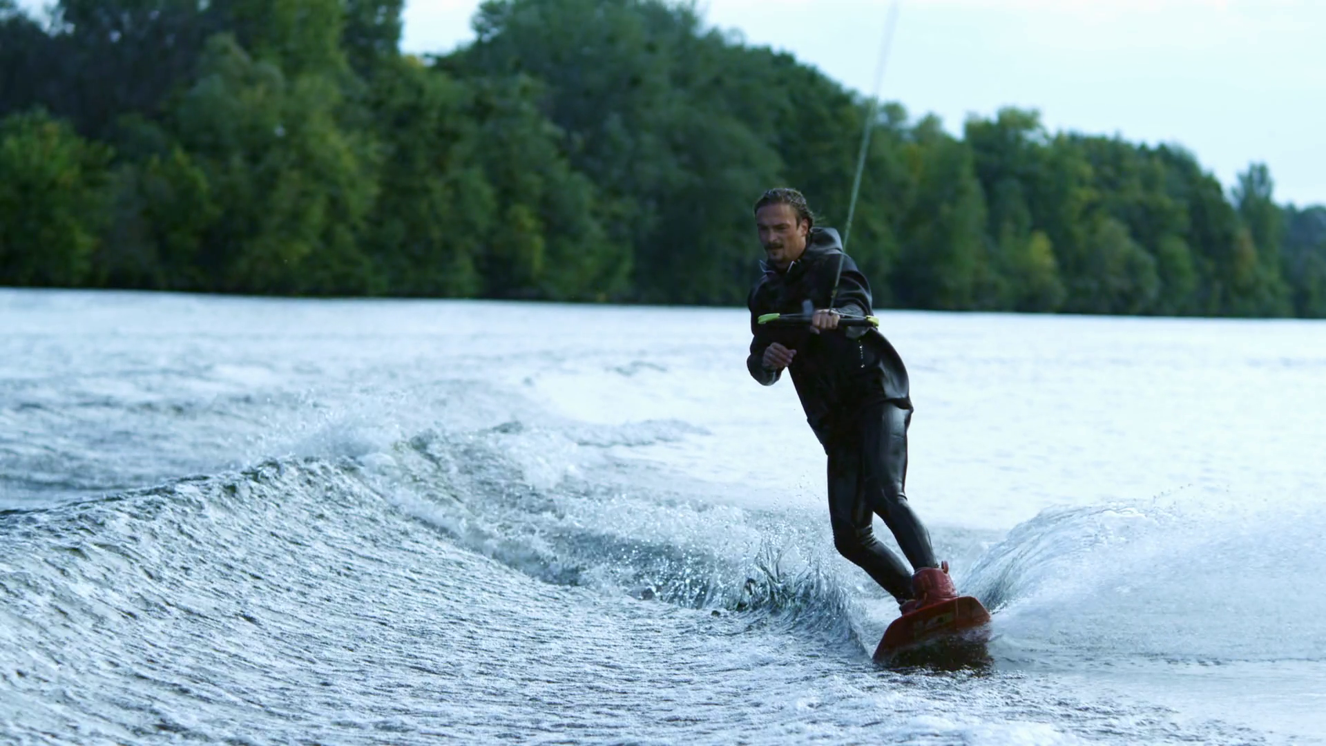 Athlete doing tricks on wakeboard. Young man wakeboarding on river wave