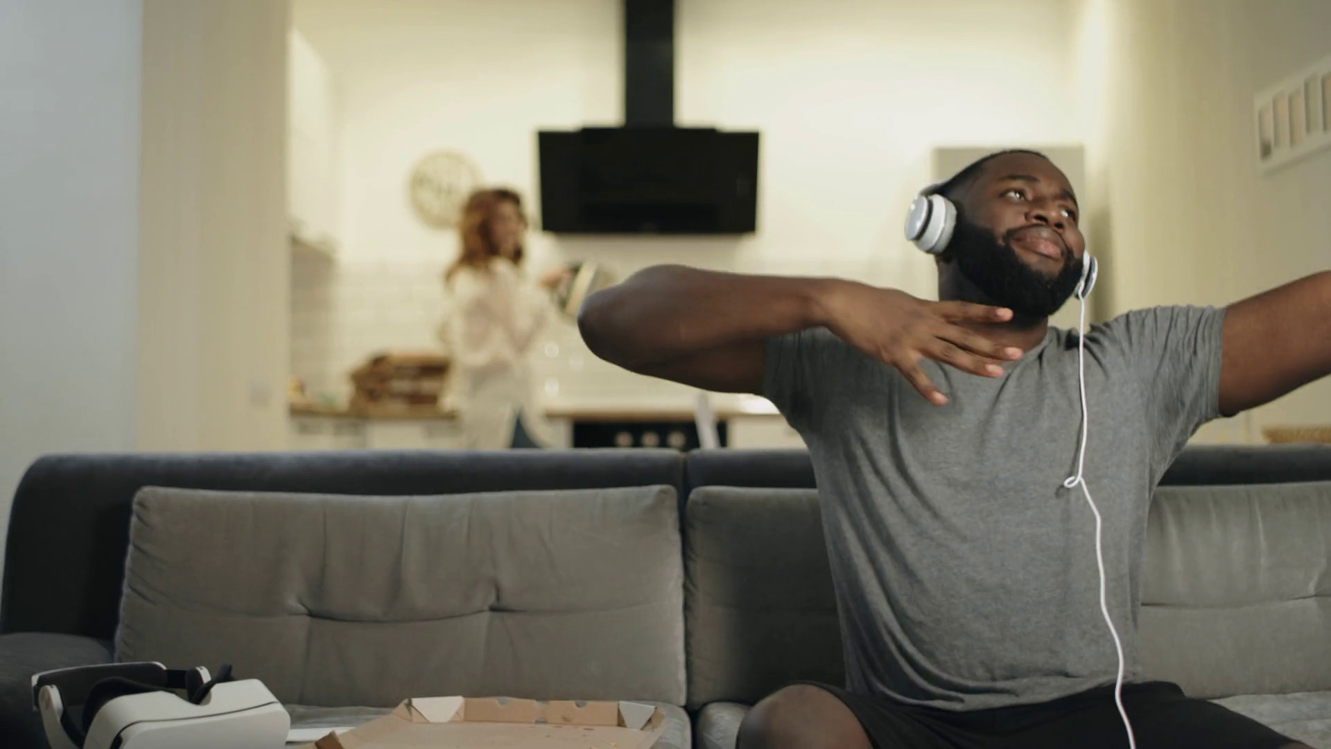 Black man dancing at home with rising hands. Funny african guy sitting