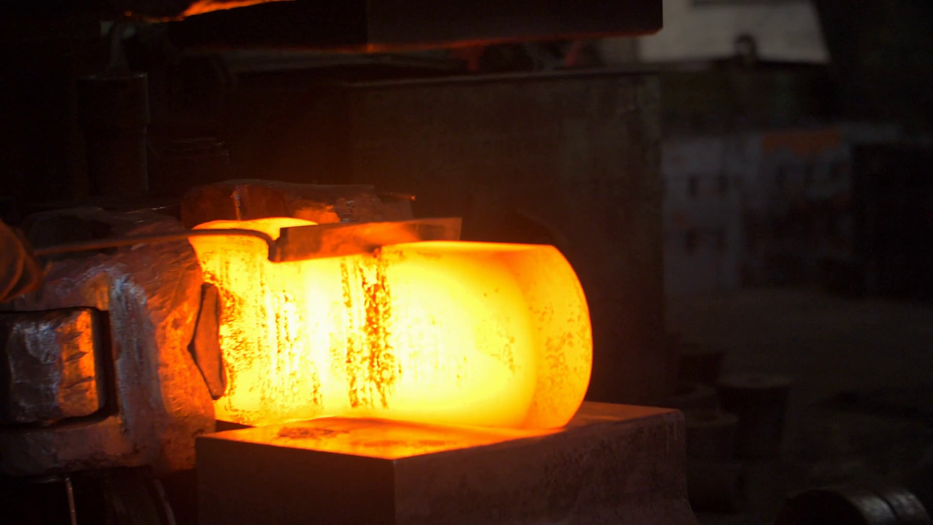 Blacksmith cutting hot metal with automatic hammer and industrial knife