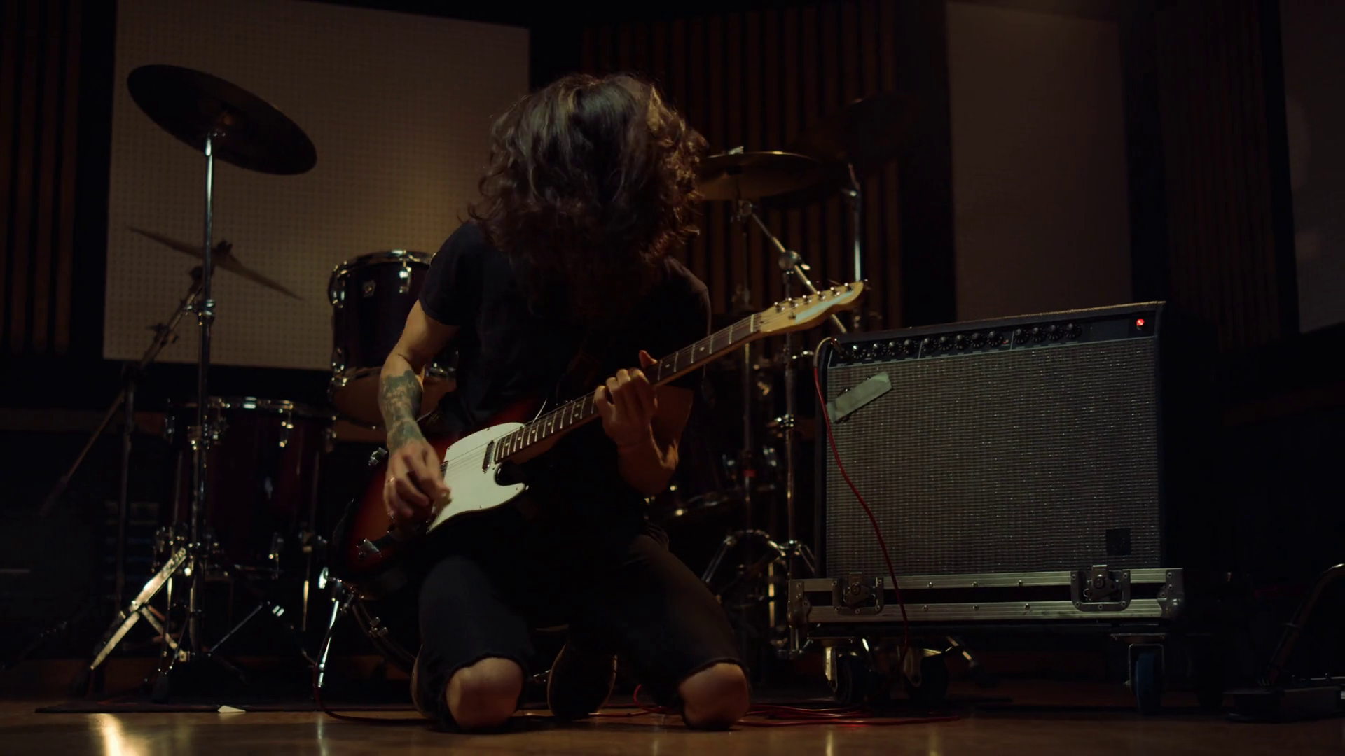 Excited guitarist dancing on knees in concert hall. Expressive artist