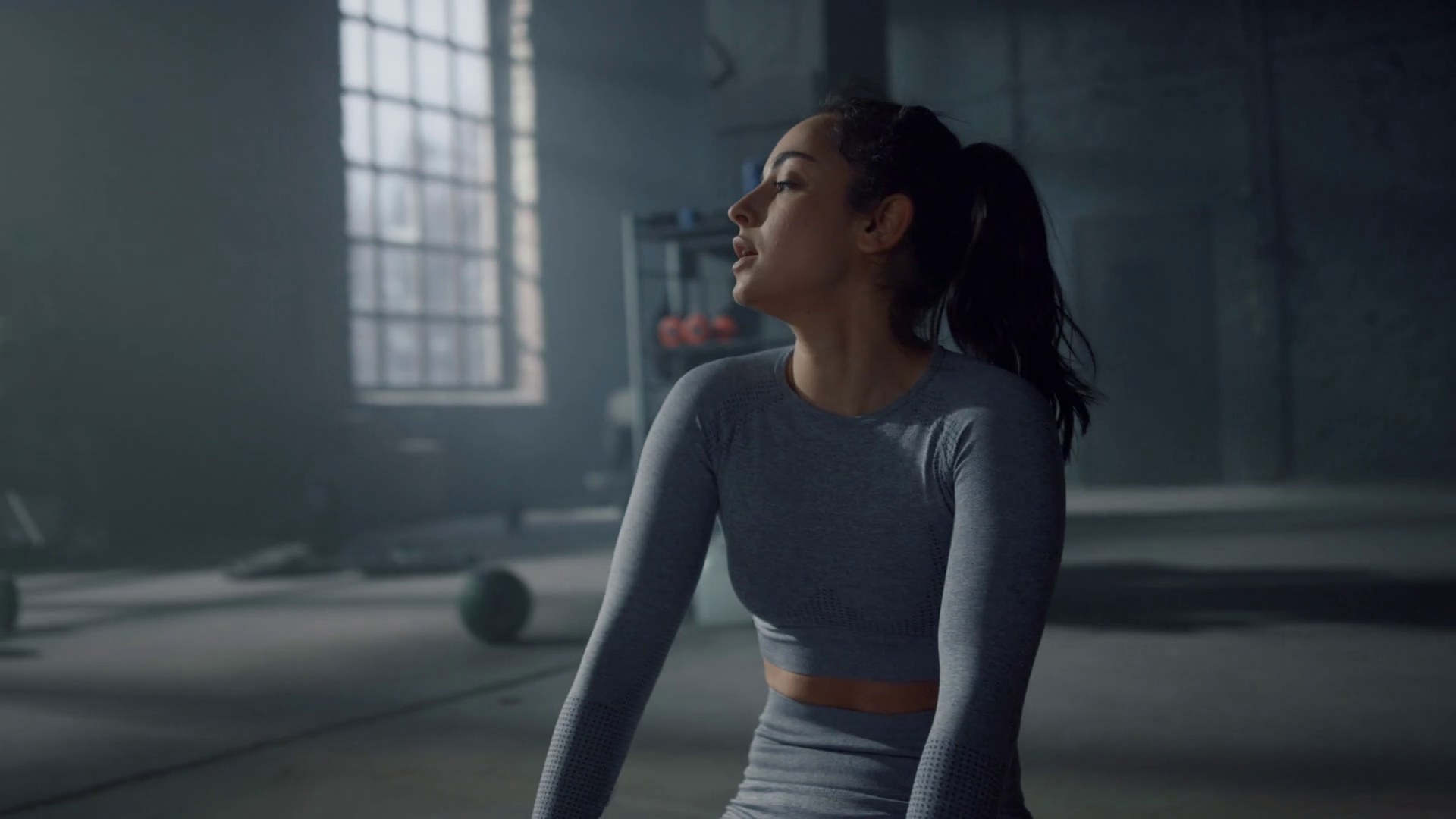 Exhausted woman sitting on floor during fitness training in gym. Female