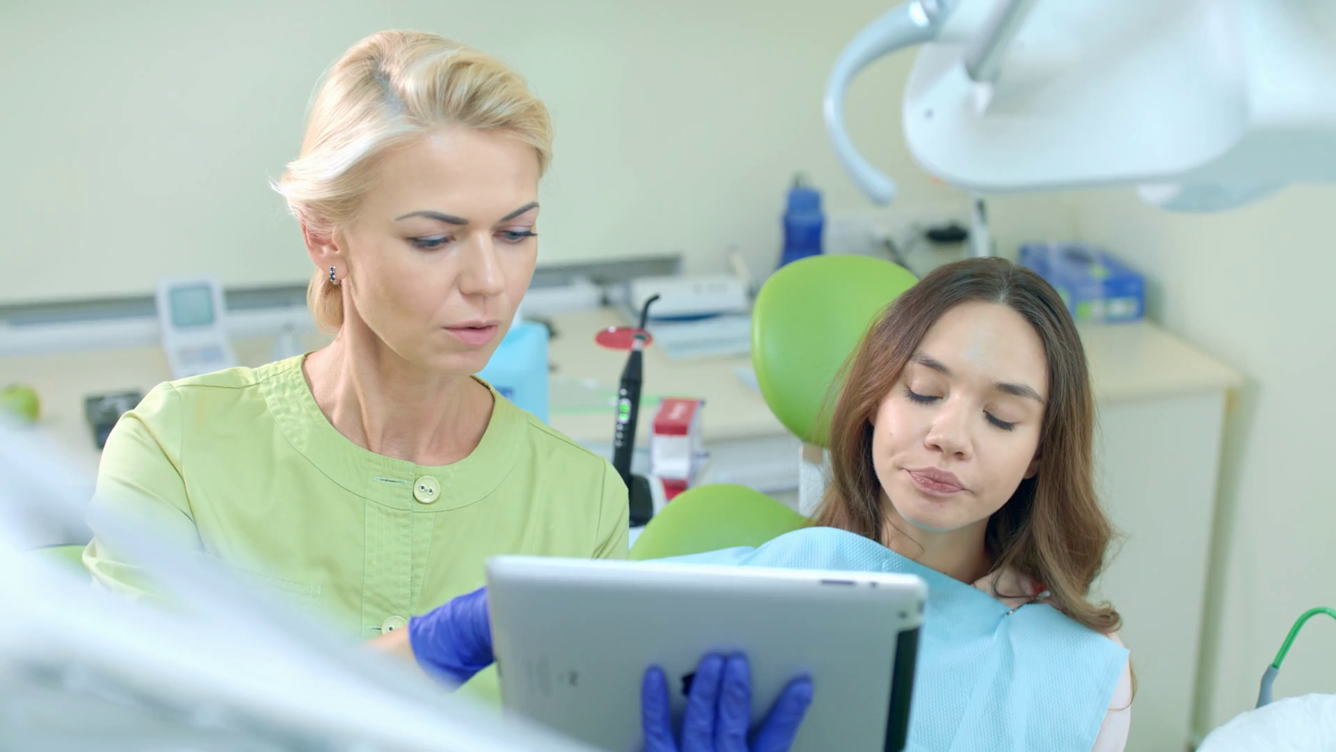 Female dentist using tablet computer. Dentist showing patient treatment
