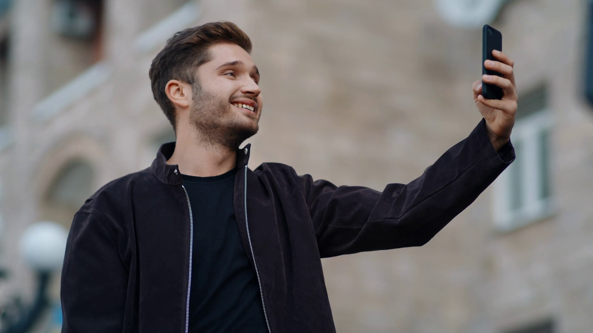 Portrait Of Grimacing Man Taking Selfie Photo By Mobile Phone In Urban Background Closeup Funny Hipster Man Looking Smartphone Screen On City Street Happy Guy Making Faces With Cellphone Outdoors Stock Video