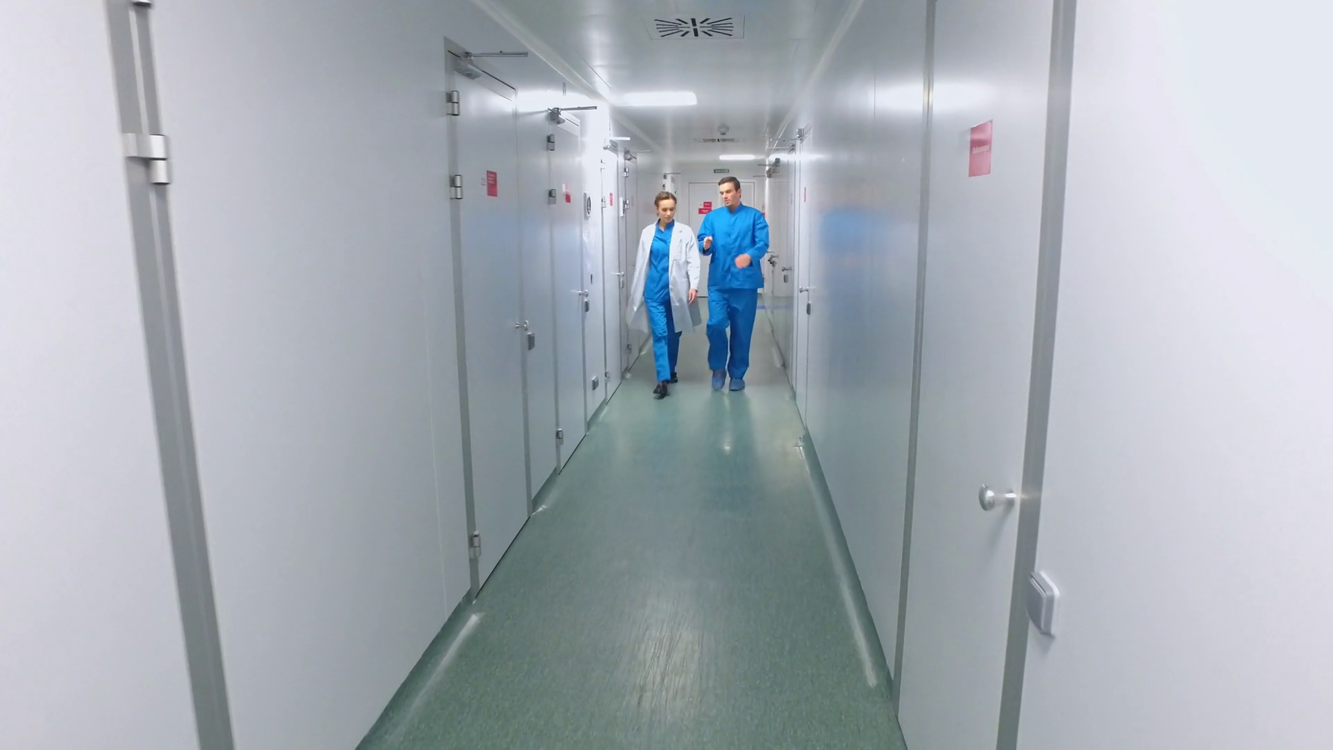 Scientists walking lab corridor. Pharmaceutical workers talking in