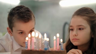 Siblings birthday cake. Close up of brother with sister looking on candle flame on dessert. Boy and girl celebration birthday together. Children birthday party