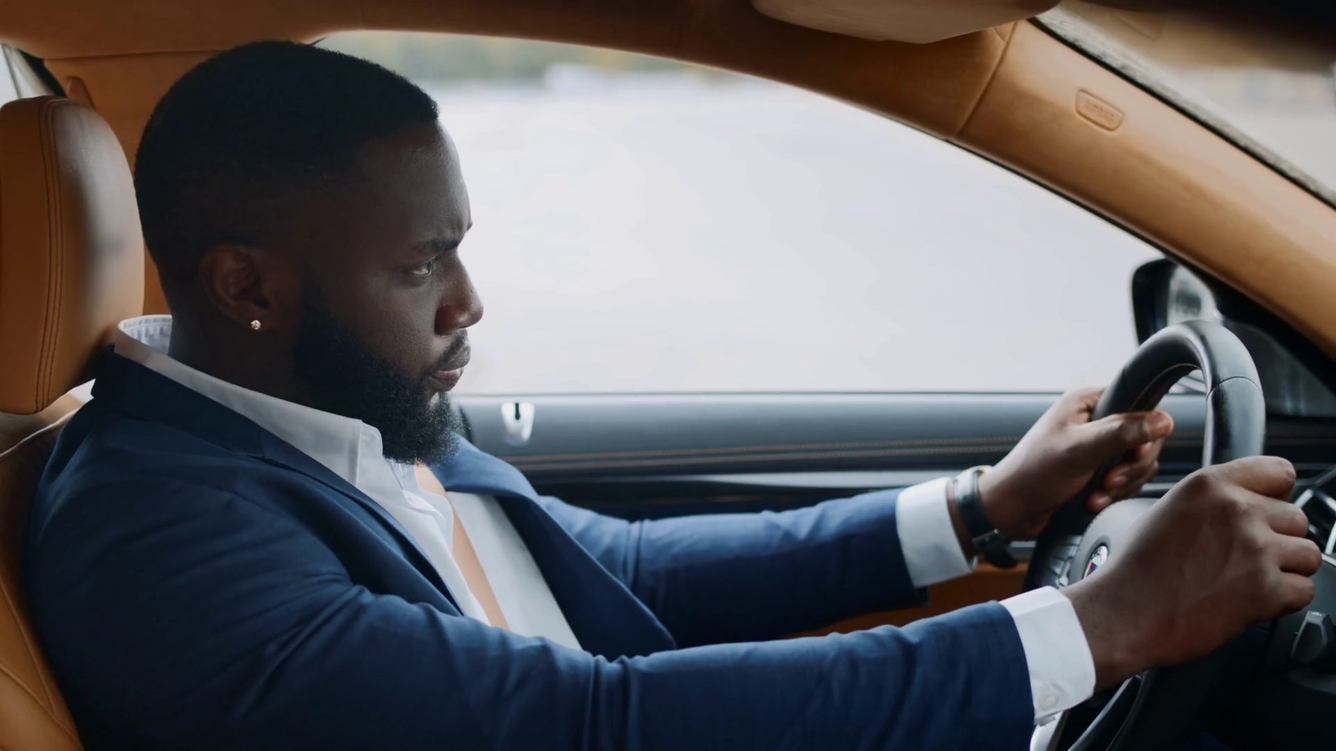 Side view of serious african businessman driving alone at luxury car