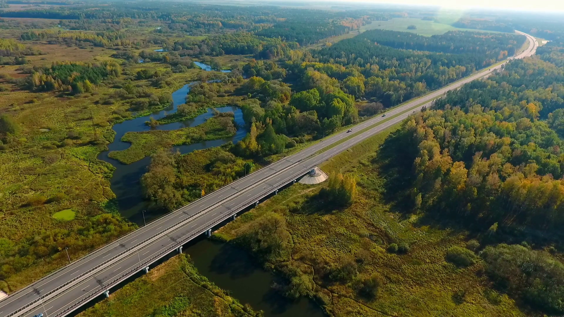Top view car bridge over river. Cars moving along bridge at nature. Highway  road above river at field. Highway road on river landscape. Aerial landscape  of cars driving on highway road at