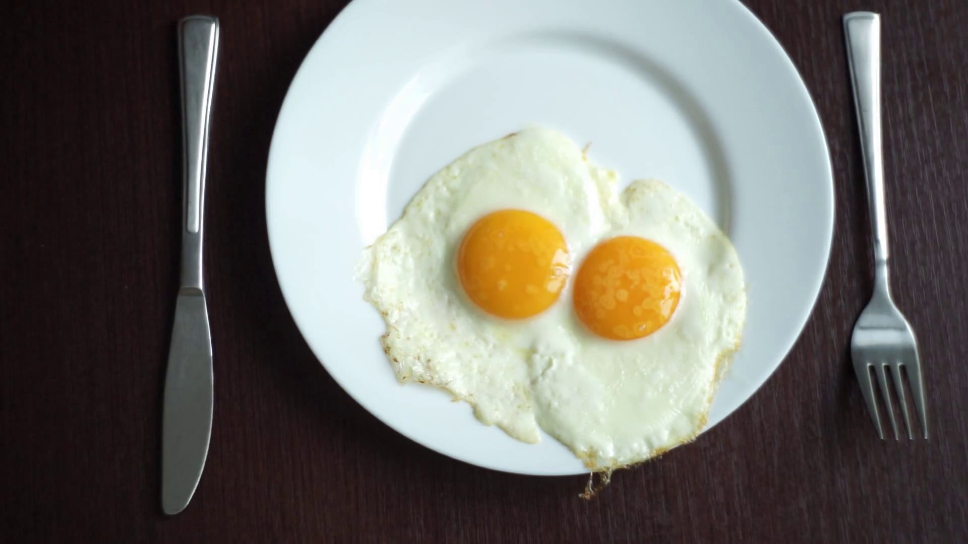 White plate with fried egg on wooden table. Serving breakfast eggs