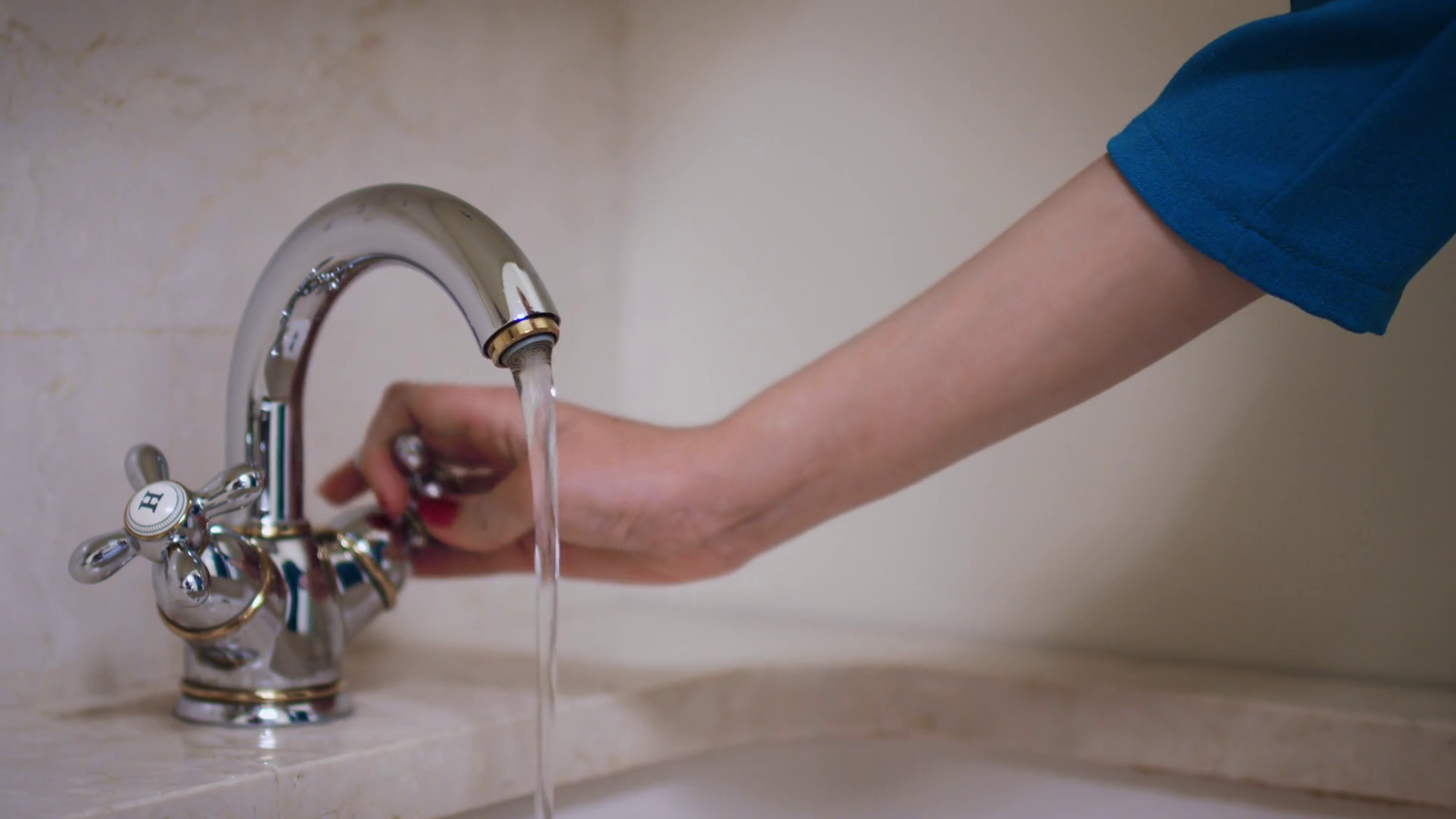 Woman hand turning knob and opening water tap in bathroom. Close up