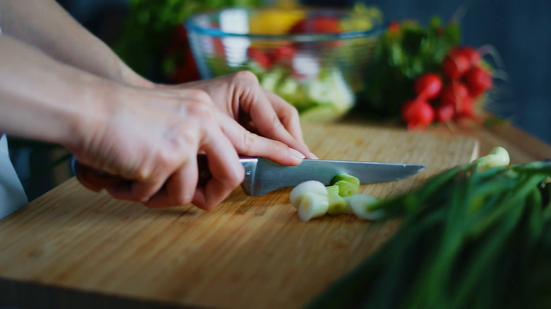 Woman hands cutting green onion for salad. Close up fresh vegetables