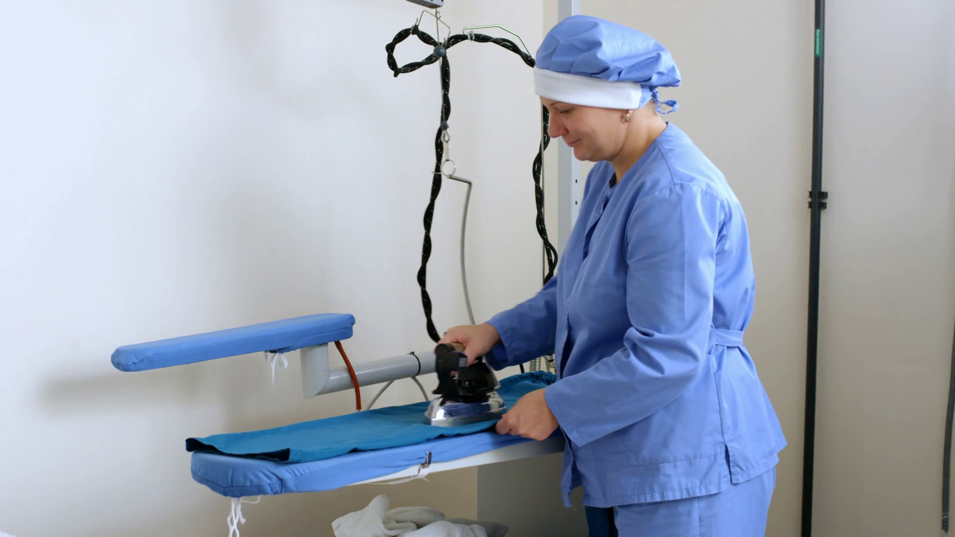 Worker woman ironing clothes with professional iron appliance. Textile