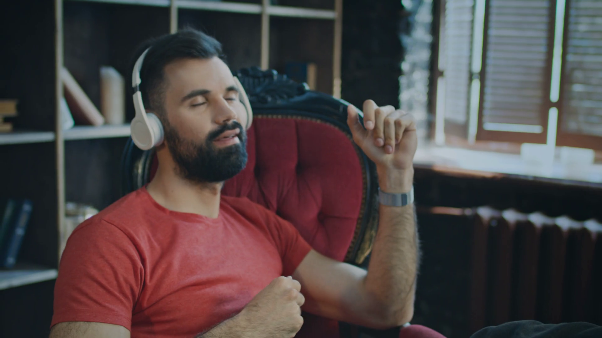 Young bearded man sitting in chair listening to music in headphones