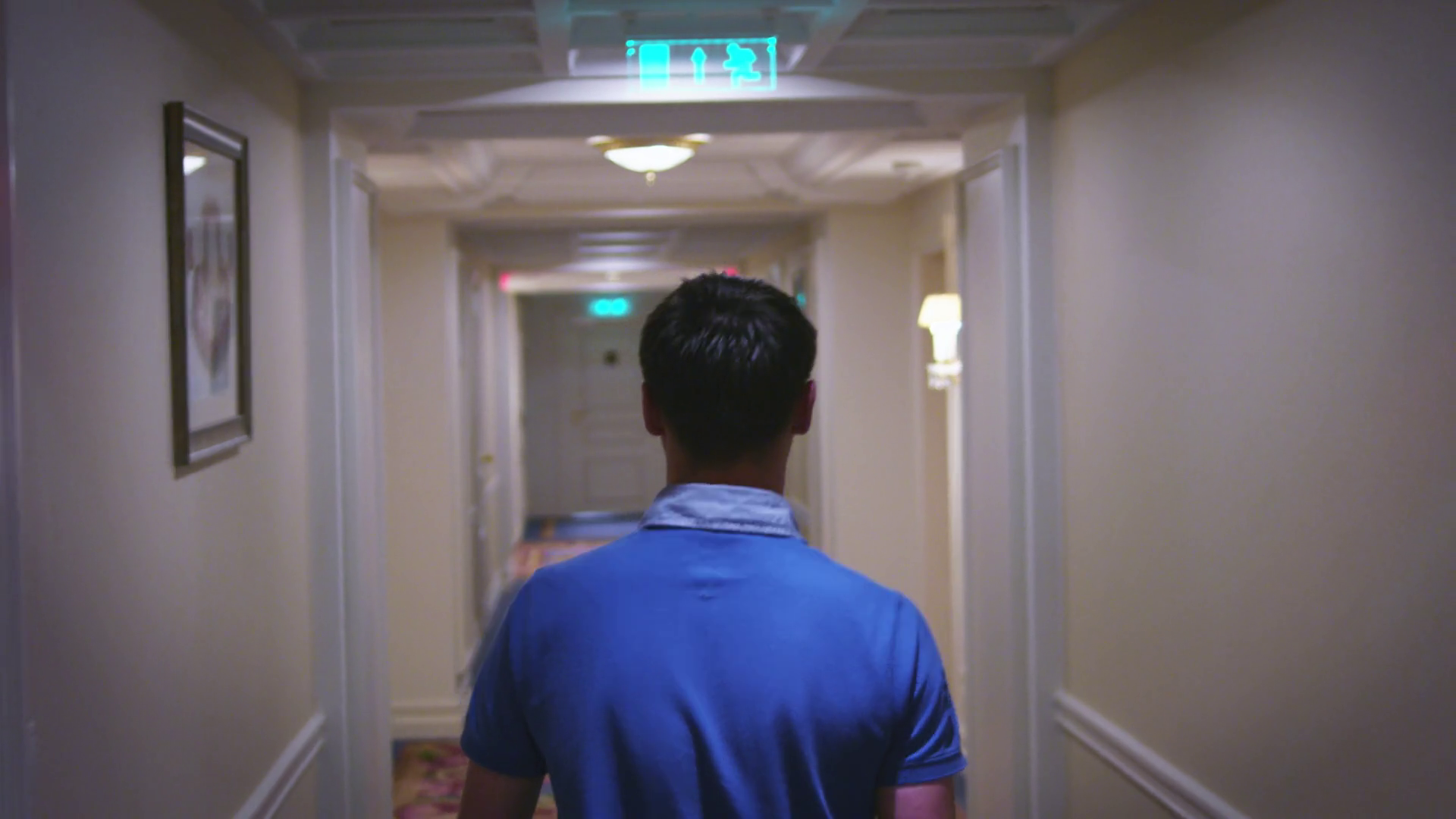 Young man walking along hallway corridor at home interior back view