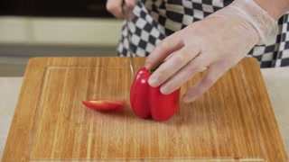 Slicing red paprika on a wooden cutting board