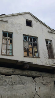 Desolate building facade with broken windows and cracked walls, a visual representation of urban decay, neglect, and the passage of time in